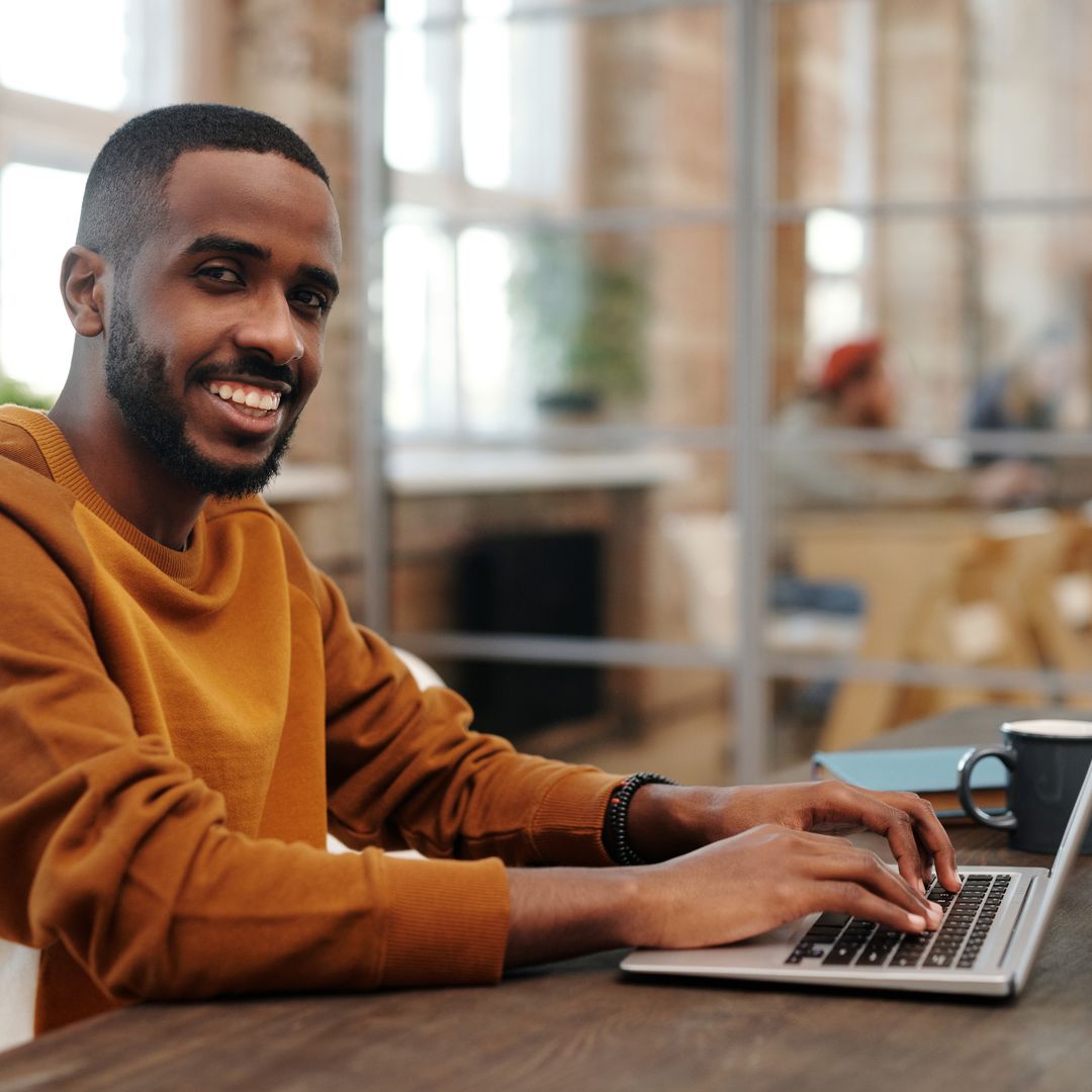 Homme souriant qui tape sur un ordinateur portable dans un bureau moderne